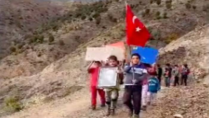 Türk bayrakları ve Atatürk fotoğrafıyla yürüyüş yapan küçük öğrenciler